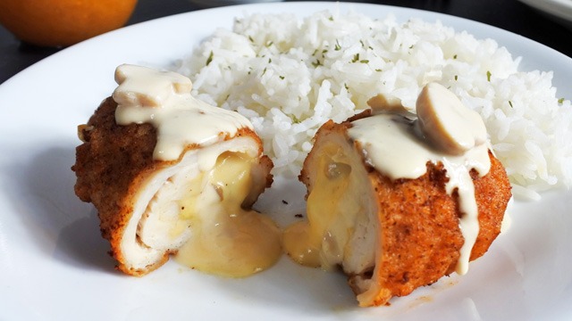 chicken mushroom cordon bleu split open with the cheese oozing out with rice on the plate