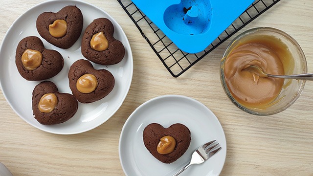 chocolate heart dessert with peanut butter filling on a plate with fork with bowl silicone mold cooling rack