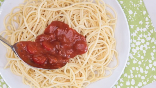 spooning sauce over cooked spaghetti